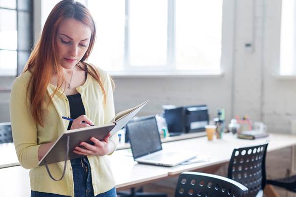 A young woman is working at a desk, writing in a notebook while surrounded by office supplies and computer equipment.

KI-generierte Inhalte können fehlerhaft sein.