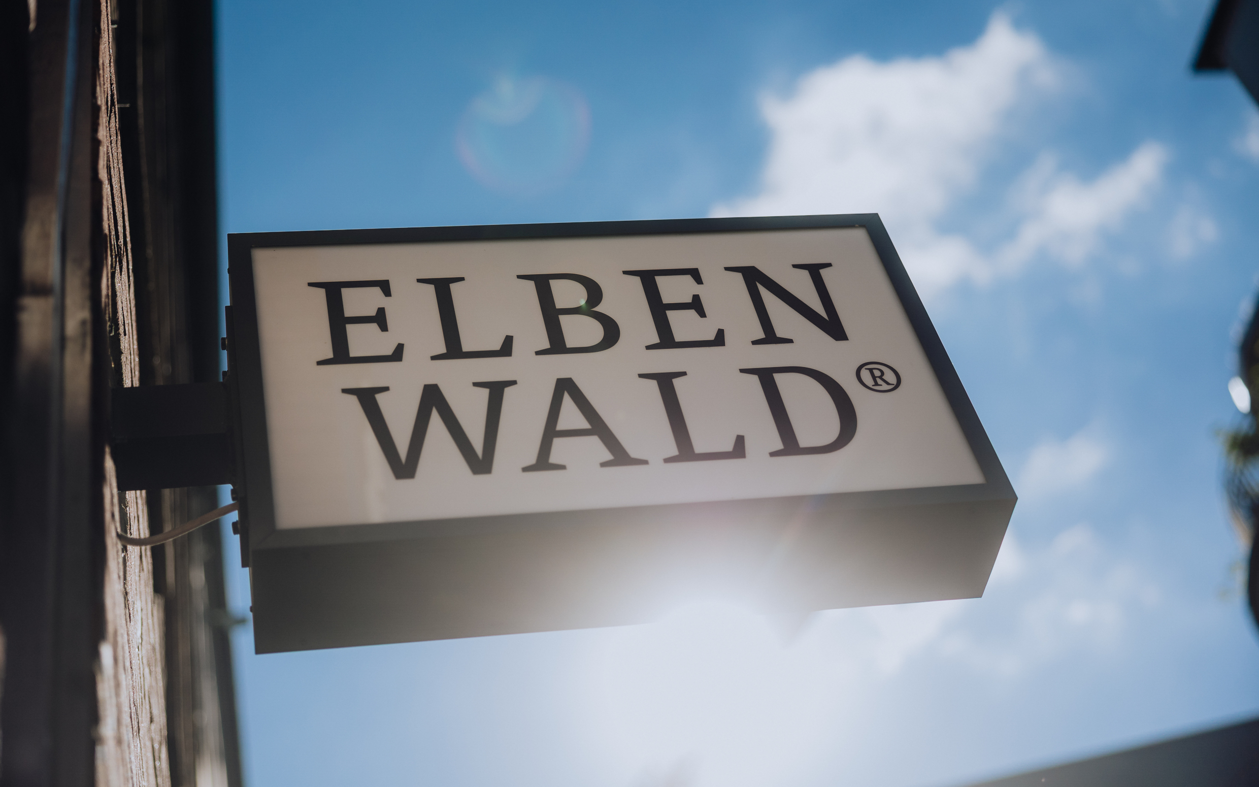 Elbenwald Store-Schild im Gegenlicht der Sonne